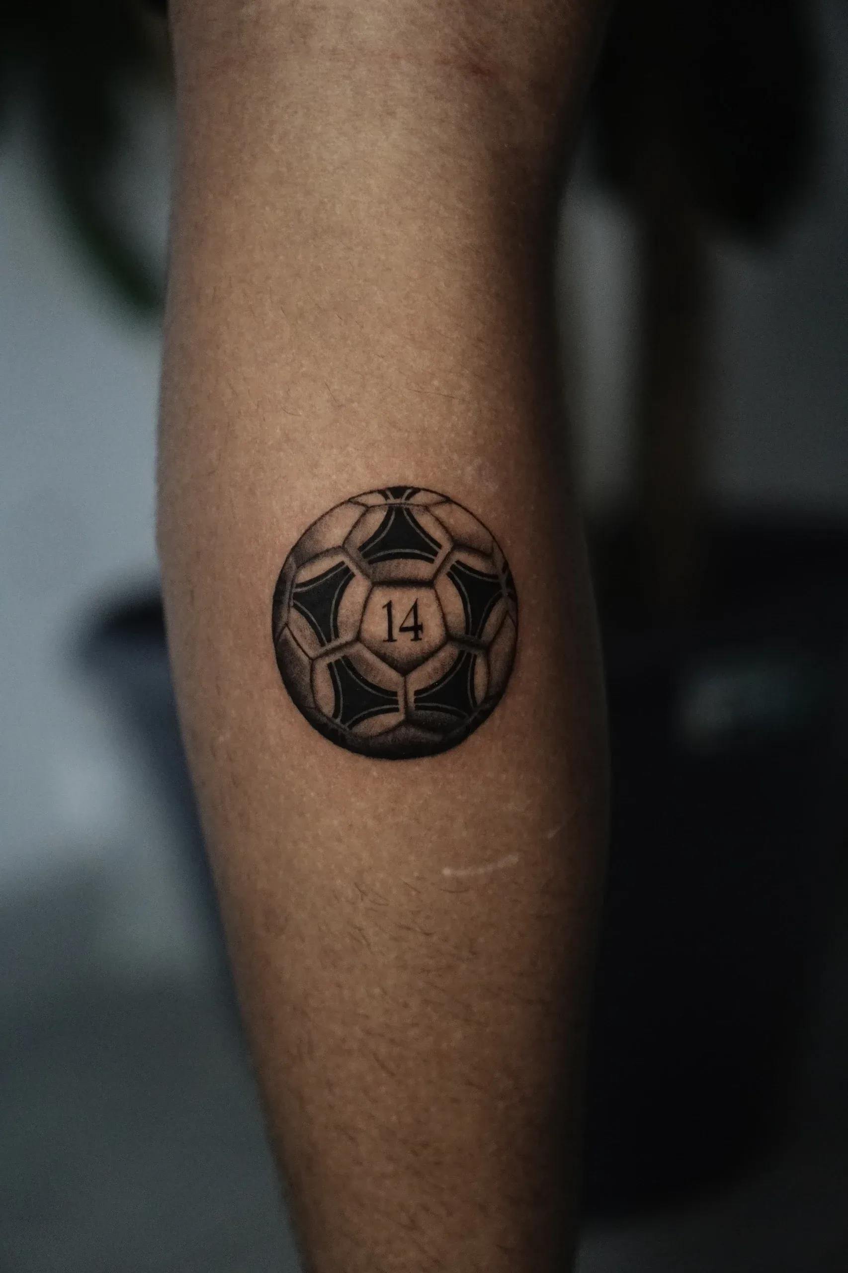 Detalle del tatuaje de balón con número 14 por Clayton Goethe